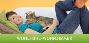 Frau mit Katze auf Schoß, gemütlich auf Sofa in gesund eingerichtetem Wohnzimmer